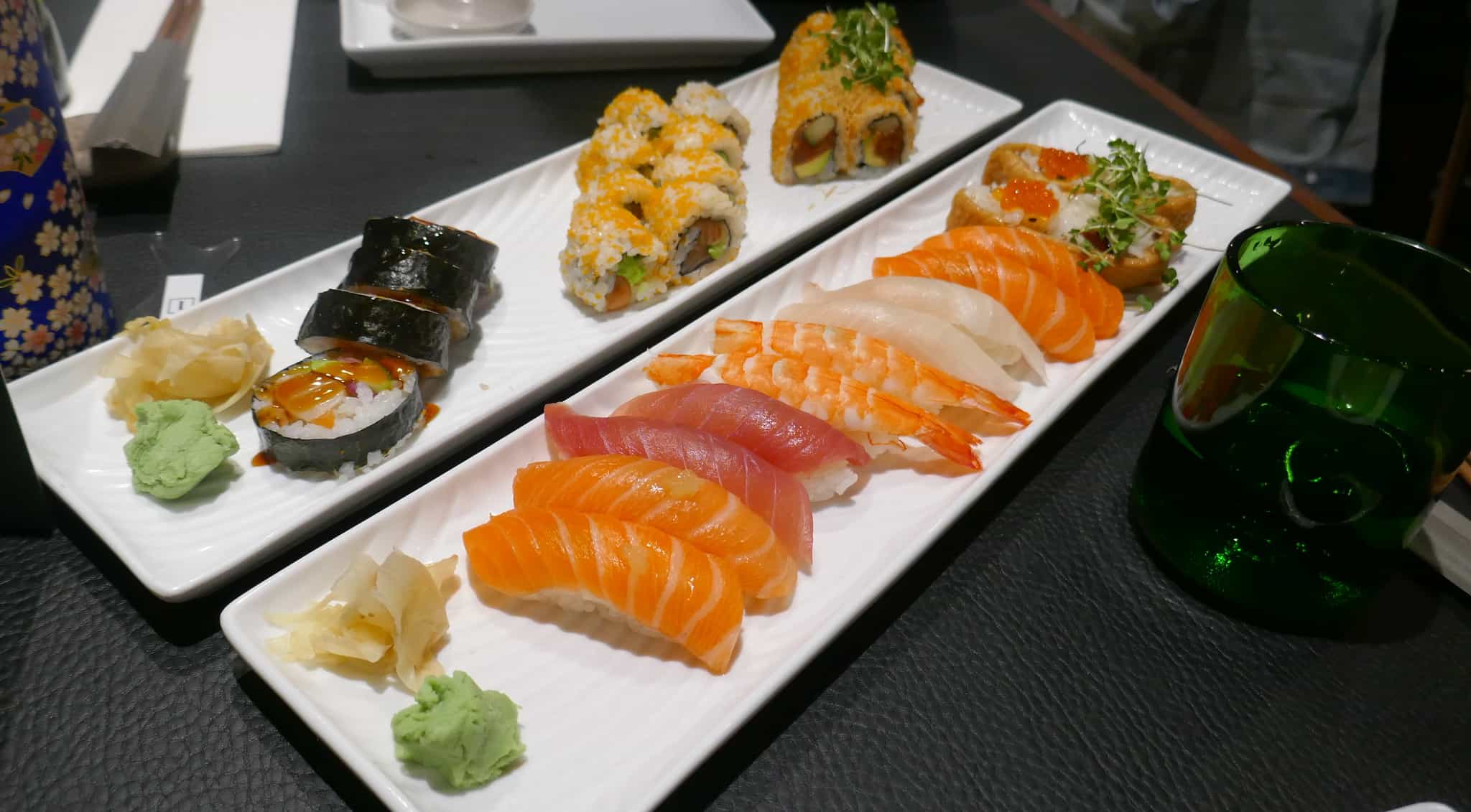 Sushi na podłużnym, białym, talerzu stojącym na czarnym stole